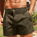 Man wearing black shorts outdoors with greenery in the background